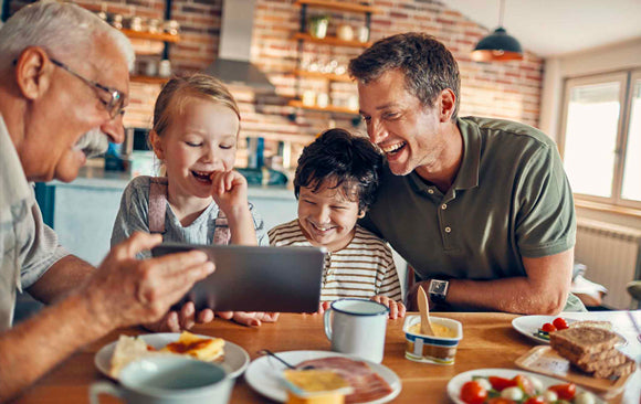 Les enfants rient avec leur père et leur grand-père au petit déjeuner